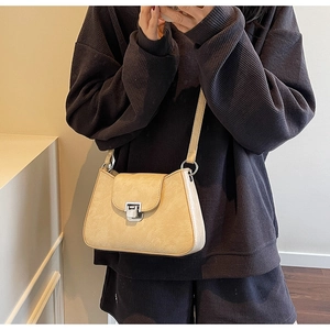 Détail du sac beige crème en similicuir avec fermoir argenté sur vêtements sombres