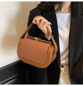 Detail of a brown leather pillow bag with contrast stitching and gold metal buckle