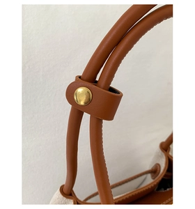 Macro detail of brown leather handle and gold metal fastener on vintage tote bag
