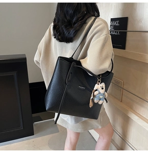Back view of a large black lychee leather tote bag with a cute bear charm pendant