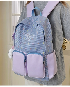 Detail of color-block backpack with blue plaid, purple straps, and bow print