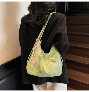 Detail of lime green leather tote with front pocket and decorative woven tassel