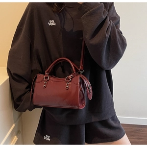 Detailansicht der weinroten Kunstledertasche mit Silbernieten und langen Leder-Zuglaschen