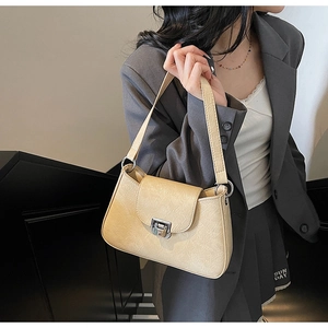 Detail of cream shoulder bag featuring leaf-vein textured leather and silver clasp