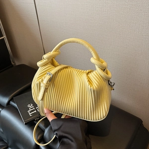 Close-up of bright yellow pleated handbag with decorative knot handles and silver hardware