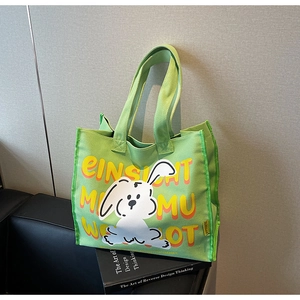 Close-up of a light green canvas tote bag with a cute rabbit print on a leather sofa