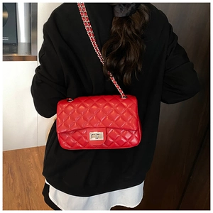 Rear view of model wearing a red quilted crossbody bag with silver chain and metal clasp