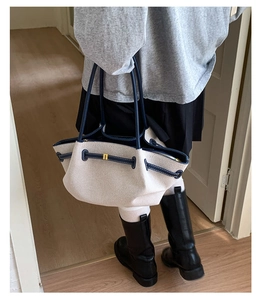 Detalle del bolso tote de lona con correas de cuero azul oscuro en el hombro de la modelo