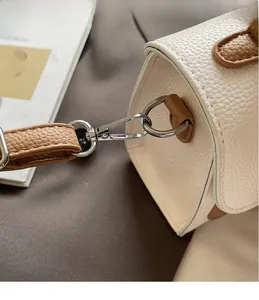 Detailed macro view of silver metallic hook and textured leather strap on the bag