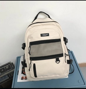 Détail d'un sac à dos crème avec poches filet posé sur une boîte de rangement bleue