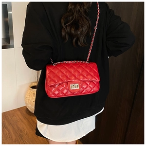 Detail of red quilted leather handbag featuring silver rectangle lock and chain strap