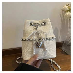 Detail of white lychee pattern bucket bag with pearl bow and silver heart charm