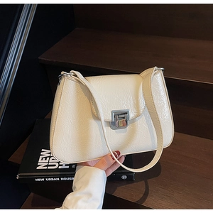 Detail of cream white underarm bag with glossy textured finish and silver metal buckle