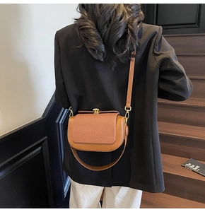 Detail of saddle brown crossbody bag with herringbone texture and gold metal clasp