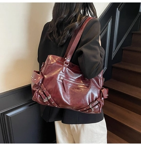 Macro detail of wine red tote bag showing glossy faux leather and vintage metal buckles