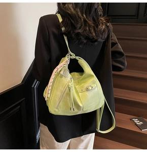 Lime green patent leather tote with metallic buckle and woven tassel on wooden stairs