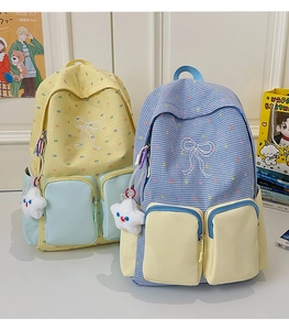 Detail of color-block plaid backpacks with bow embroidery and plush star pendants