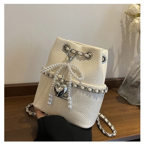 White bucket bag with lychee texture leather, pearl bow, and silver heart charm detail