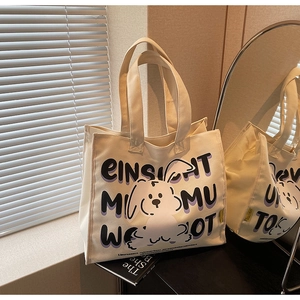 Detailed close-up of a cream canvas tote bag with cartoon rabbit and letter printing