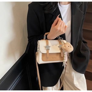 Détail du sac bandoulière contrasté avec boucle étoile en métal et pendentif ours