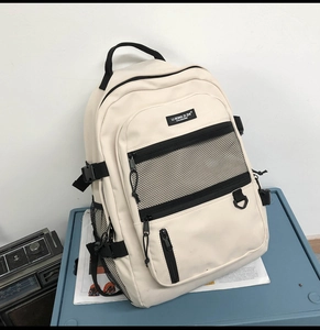 Détail du sac à dos en nylon blanc cassé avec poche en filet et sangles à boucles