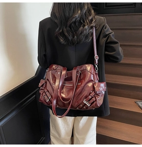 Macro detail of burgundy tote bag showing soft leather texture and metallic buckle accents