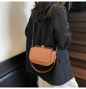 Detail of retro brown crossbody bag featuring textured fabric flap and gold lock hardware