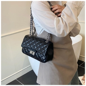 Close-up of black quilted leather shoulder bag with silver chain strap and metal lock