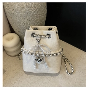 Detail of white lychee leather bucket bag with silver chain and pearl bow pendant