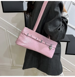 Close-up of pink patent leather shoulder bag with silver heart charm and buckle detail
