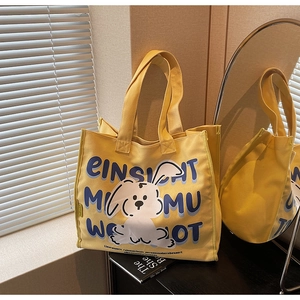 Detail of a bright yellow canvas tote bag with a blue rabbit print on a wooden table