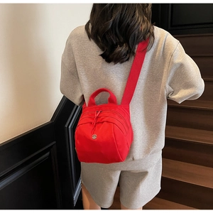 Detail of a red multi-layer waterproof nylon crossbody bag with wide shoulder strap