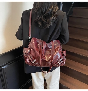 Detail of dark red vintage tote bag with multiple zippers and metallic buckles