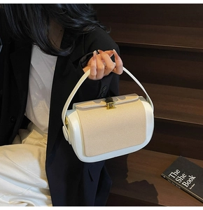 Detail of a color-block pillow bag featuring beige woven texture and a gold metal lock