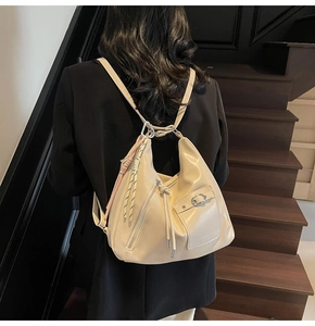 Detail of off-white faux leather hobo bag with silver zippers and soft pleated texture
