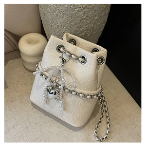 Detail of white bucket bag featuring lychee texture and pearl bow with silver heart pendant