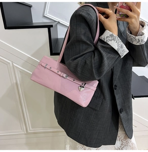 Detail of pink faux leather underarm bag with silver heart charm and buckle strap
