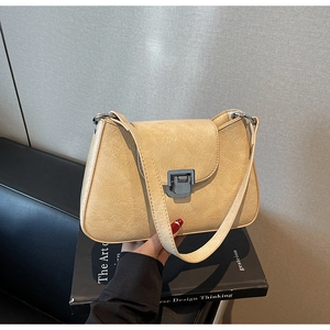 Detail of a beige vintage textured leather crossbody bag with silver square metal buckle