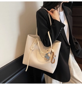 Detail of off-white lychee grain leather tote bag with cute bear charm for daily commute