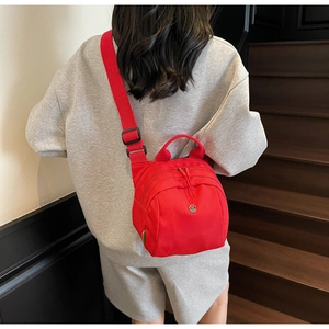 Detail of red nylon shell-shaped crossbody bag with adjustable wide strap and handle