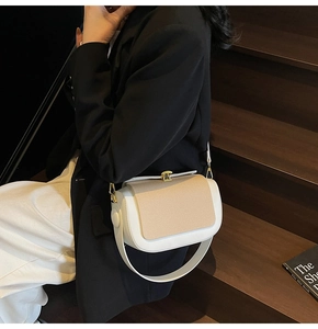 Detail of color-block pillow bag with woven texture and gold clasp on a minimalist background