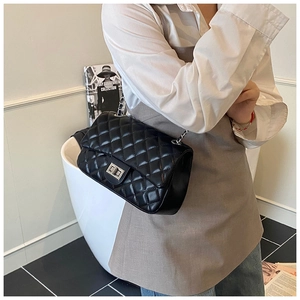 Detail of black quilted leather texture with gold metal chain and square turn-lock closure