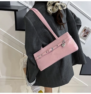 Close-up of pink patent leather baguette bag featuring a silver heart charm and buckle