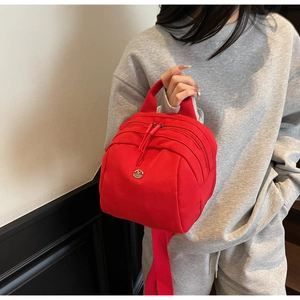 Detail of red mini canvas shell bag with triple zippers and metallic M logo