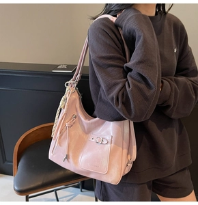 Close-up of light pink glossy tote bag with metal buckle pocket and fringe tassel