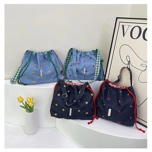 Close-up of four denim bucket bags featuring floral and cherry embroidery with drawstrings