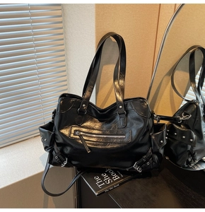 Detail of a large black vintage tote bag with side pockets and glossy faux leather texture