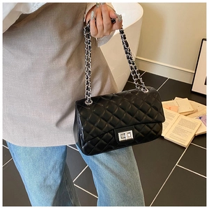 Detail of black quilted leather shoulder bag with silver chain strap and twist lock