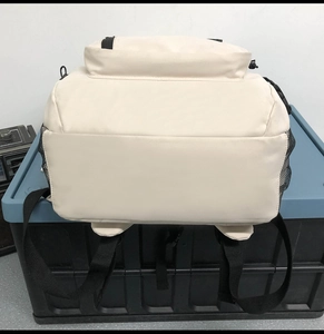 Détail d'un sac à dos crème montrant le fond spacieux et la poche latérale en filet