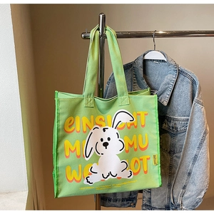 Detail of green canvas tote bag with cartoon rabbit print and artistic lettering